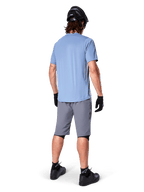 Alpinestars A-Dura shorts, mørkegrå MTB-shorts, set bagfra, båret med en lyseblå kortærmet trøje og sort mountainbike-hjelm, sorte handsker og strømper med sorte sko, funktionelt og holdbart gear til terrænkørsel