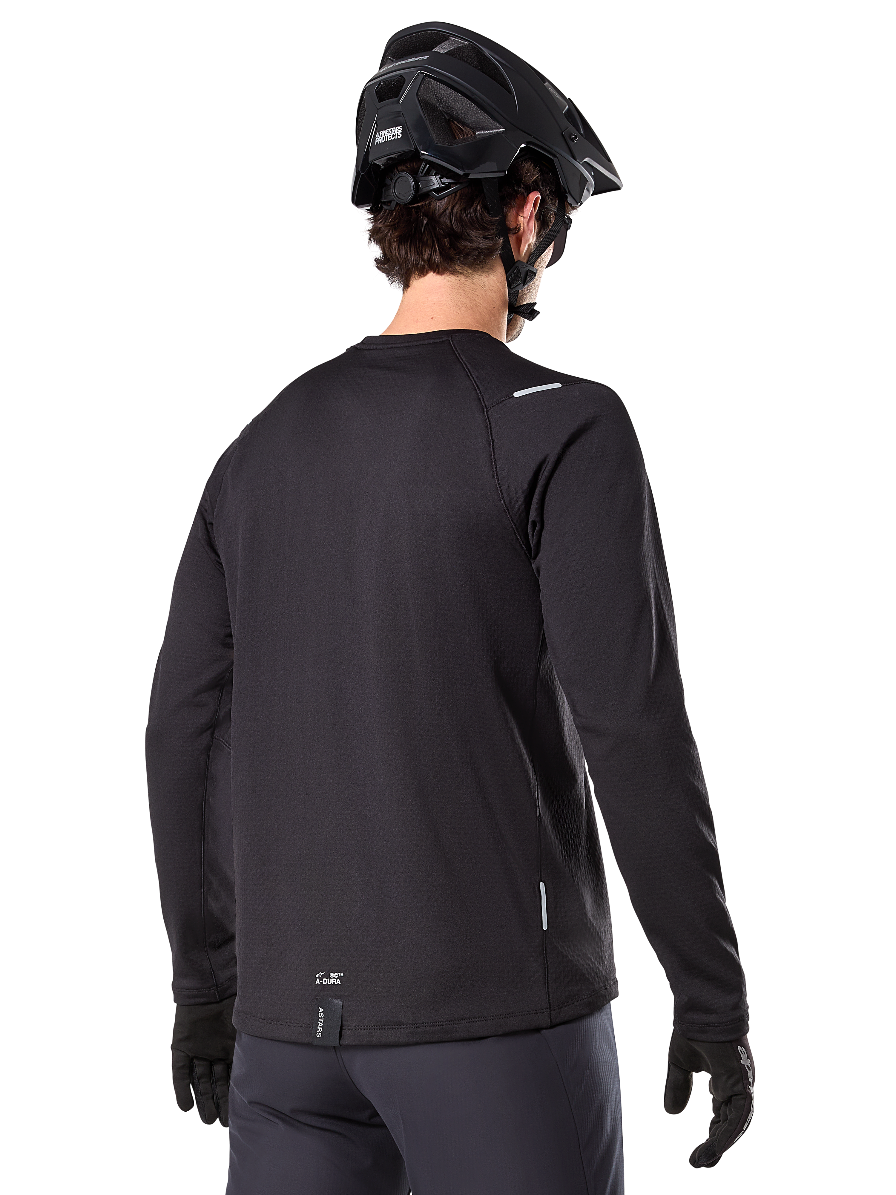 Alpinestars A-Dura Thermal Jersey, langærmet mountainbike-trøje, sort, set bagfra som viser forlænget drop tail, små refleksdetaljer og branding ved sømmen, båret med en sort hjelm og handsker til cykling i koldt vejr