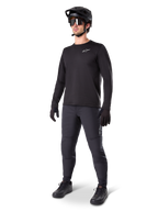 Model iført Alpinestars A-Dura Thermal Jersey, sort langærmet MTB-trøje, sort mountainbike-hjelm, solbriller og mørkegrå bukser, med et lille hvidt logo på brystet, isoleret fleece-konstruktion til kørsel i koldt vejr