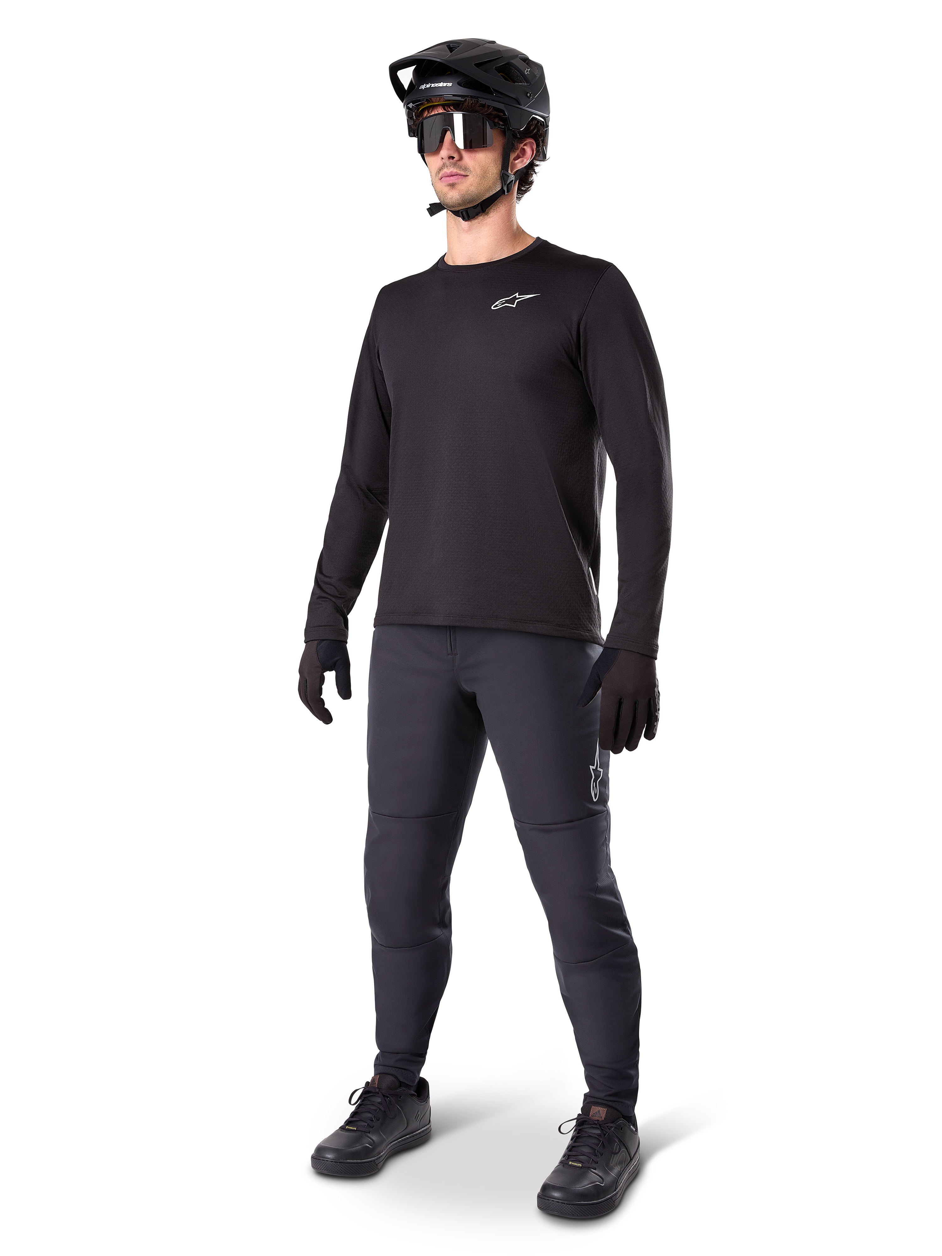 Model iført Alpinestars A-Dura Thermal Jersey, sort langærmet MTB-trøje, sort mountainbike-hjelm, solbriller og mørkegrå bukser, med et lille hvidt logo på brystet, isoleret fleece-konstruktion til kørsel i koldt vejr