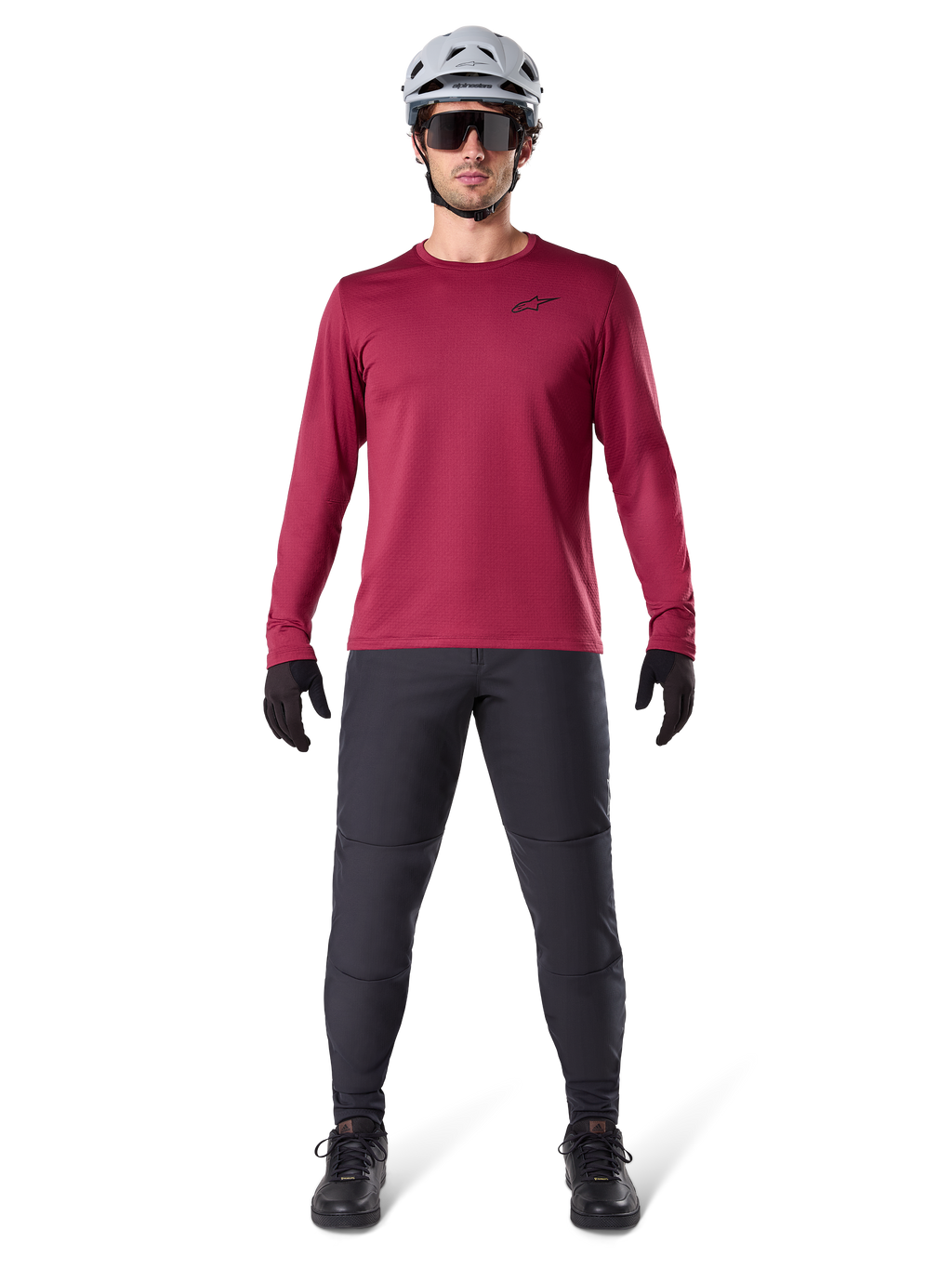 Mandlig model iført Alpinestars A-Dura Thermal Jersey i Burgundy, langærmet isoleret cykeltrøje, kombineret med mørkegrå mountainbike-bukser, hvid hjelm, sorte solbriller og sorte handsker, professionelt MTB-udstyr til koldt vejr