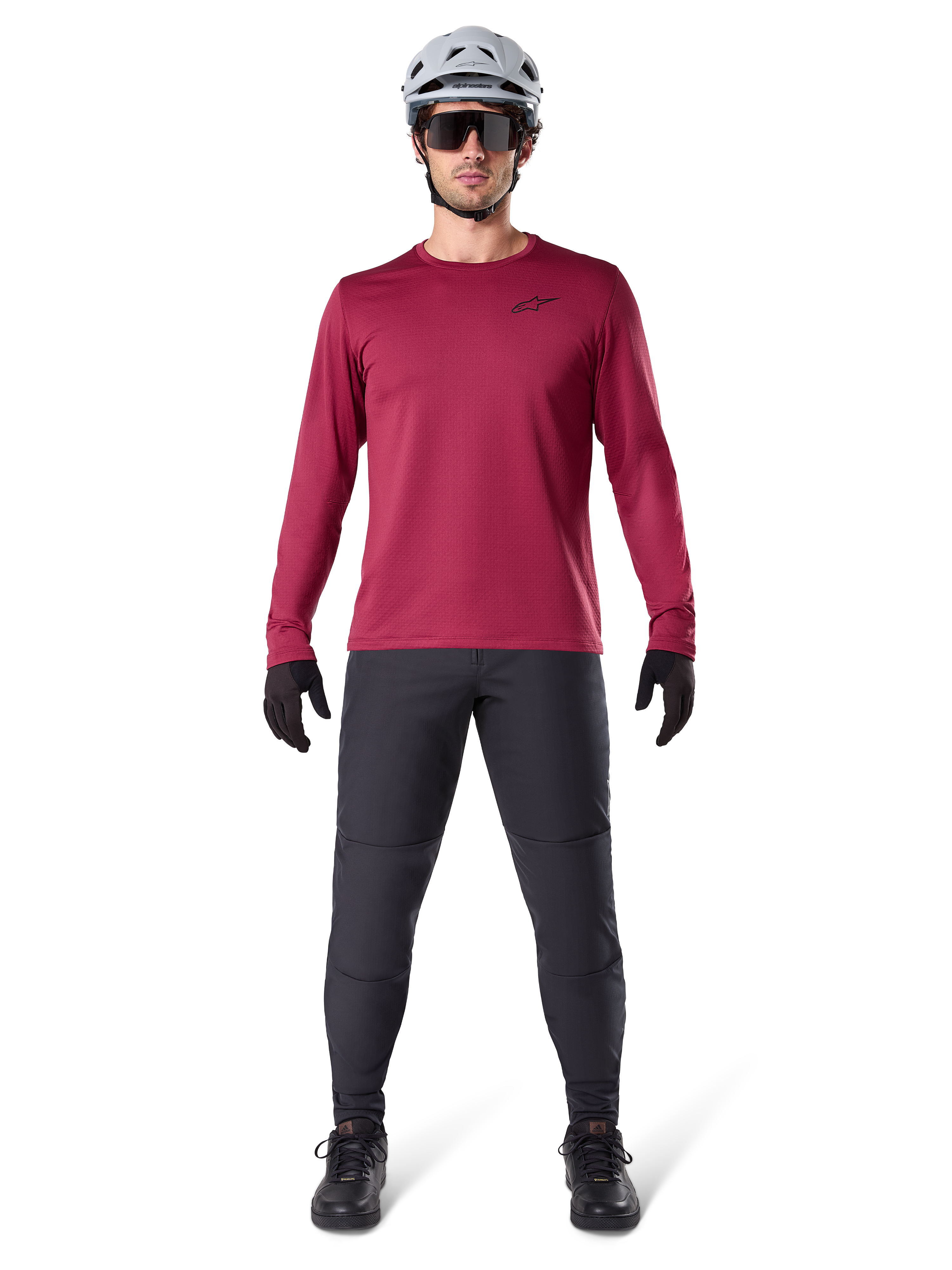 Mandlig model iført Alpinestars A-Dura Thermal Jersey i Burgundy, langærmet isoleret cykeltrøje, kombineret med mørkegrå mountainbike-bukser, hvid hjelm, sorte solbriller og sorte handsker, professionelt MTB-udstyr til koldt vejr
