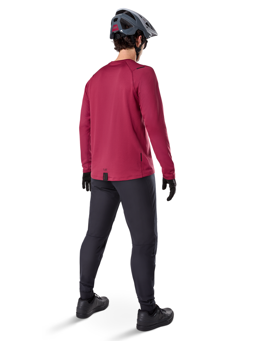 Alpinestars A-Dura Thermal Jersey, vinrød langærmet cykeltrøje, set bagfra, båret med sorte mountainbike-bukser og en grå hjelm, med en forlænget drop tail-kant for dækning bagtil, mountainbike-udstyr til koldt vejr