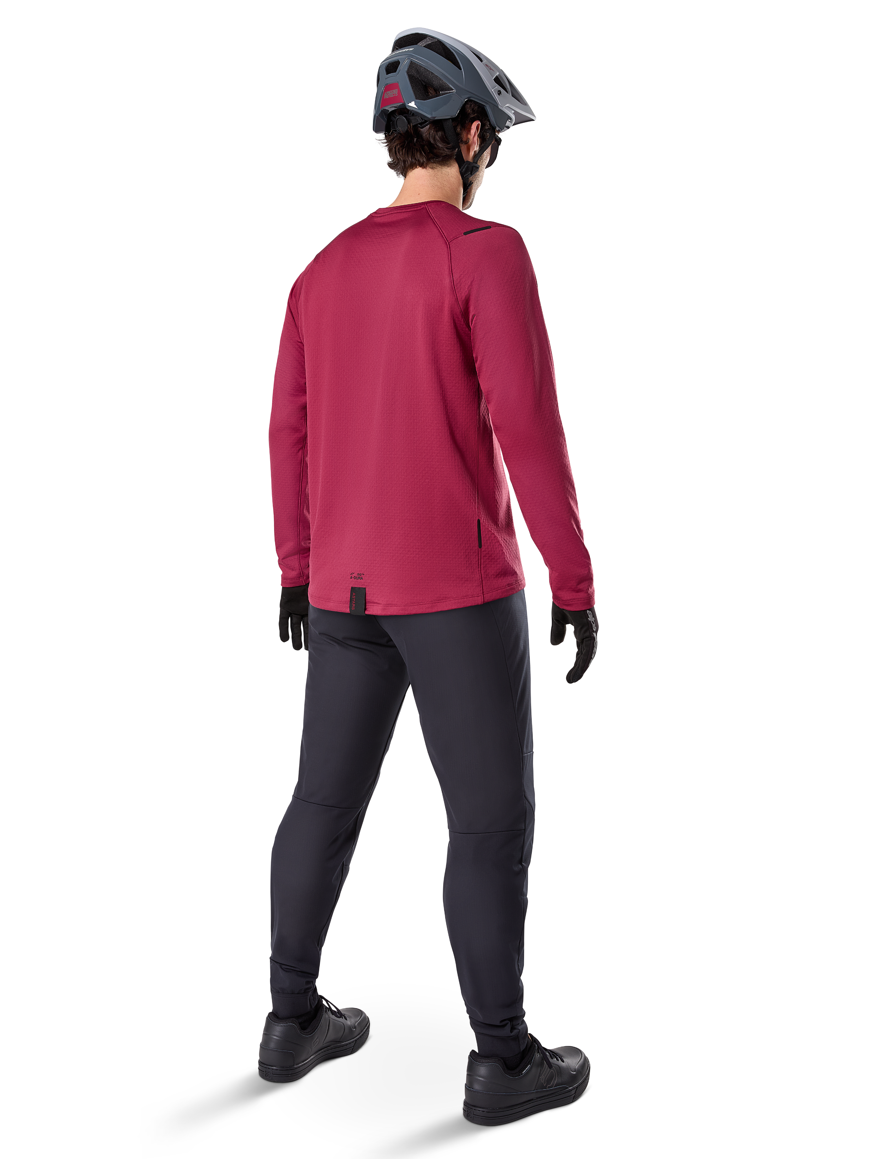 Alpinestars A-Dura Thermal Jersey, vinrød langærmet cykeltrøje, set bagfra, båret med sorte mountainbike-bukser og en grå hjelm, med en forlænget drop tail-kant for dækning bagtil, mountainbike-udstyr til koldt vejr