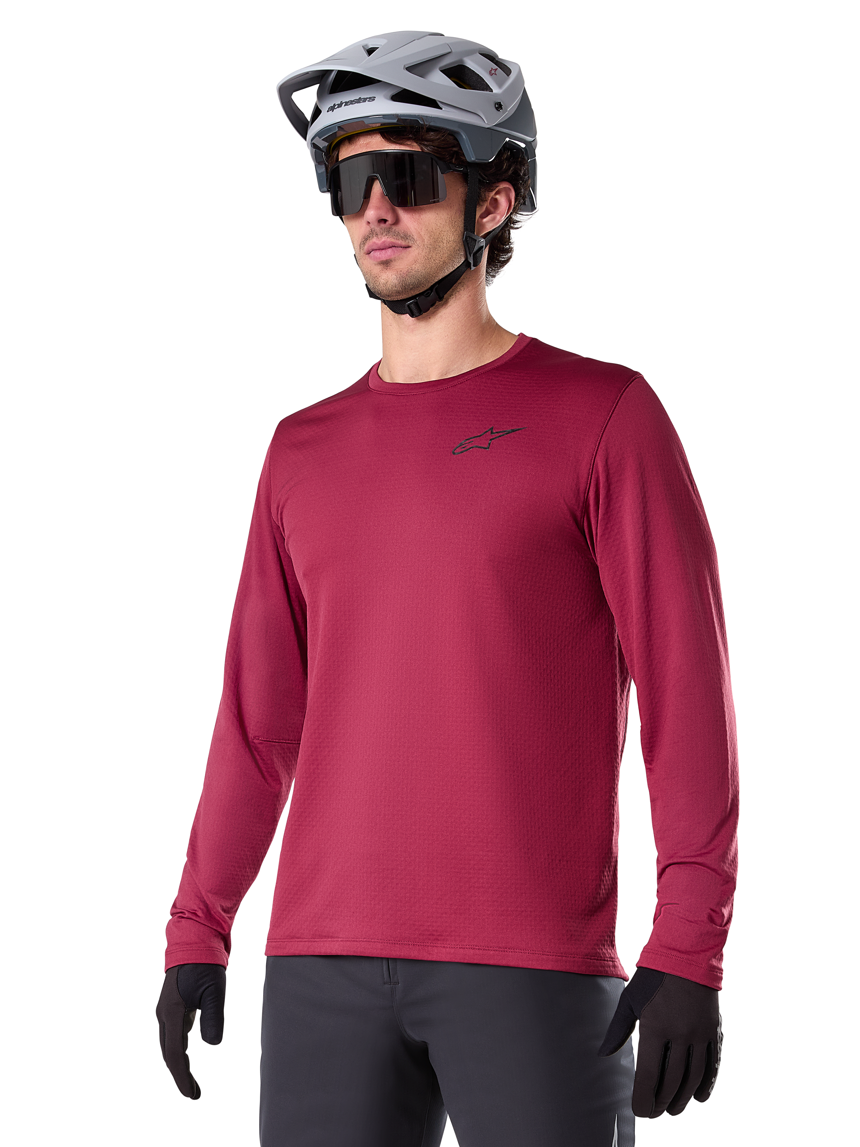 Alpinestars A-Dura Thermal Jersey, langærmet mountainbike-trøje, burgundy-rød, med isolerende fleece-for og lille sort logo på brystet, vist med grå hjelm, sorte solbriller og sorte handsker, designet til cykling i koldt vejr