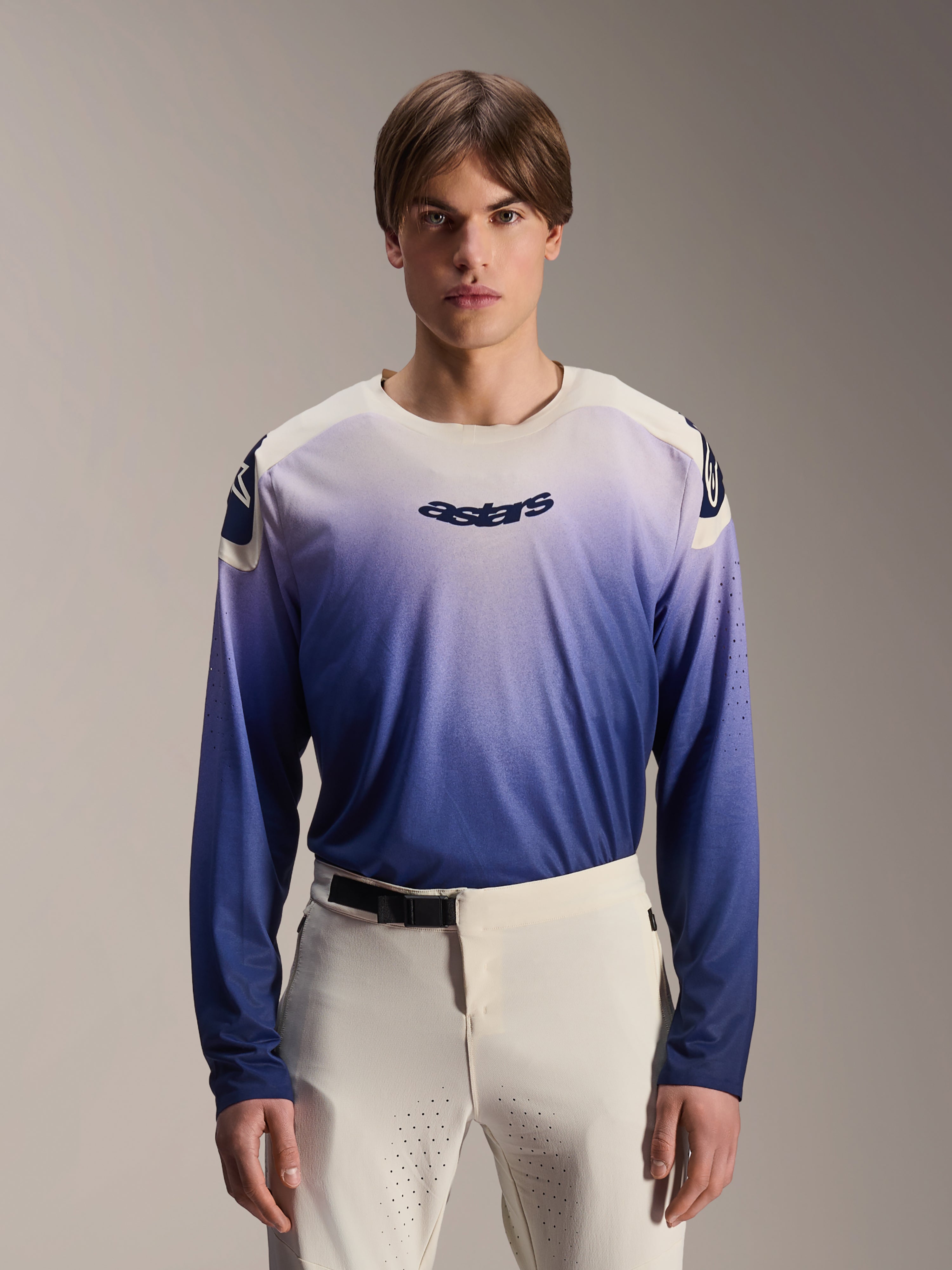 Alpinestars A-Aria Polartec Maker Elite trøje, langærmet MTB-trøje, Baja Blue med hvid-til-blå gradient, båret af en model med hvide bukser, med mørkeblåt logo på brystet og laserperforeringer på ærmerne, performance mountainbike-beklædning