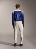 Alpinestars A-Aria Polartec Maker Elite langærmet trøje, Baja Blue og råhvid, set bagfra af model iført teknisk mountainbike-udstyr, råhvide bukser med Alpinestars-branding på underbenene, performance cykeloutfit til off-road stier