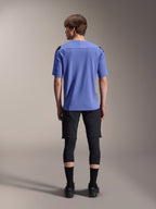 Mountainbikerytter set bagfra iført Alpinestars A-Aria Lite Shorts i sort, kombineret med en blå kortærmet jersey, sorte knæbeskyttere og sorte strømper, performance-cykeludstyr til off-road trails