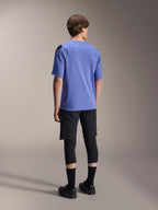 Alpinestars A-Aria Polartec Elite kortærmet jersey i Baja Blue, set bagfra på en mandlig model, parret med sorte MTB-shorts og knæbeskyttelse, med performance-pasform og forlænget rygstykke til trailkørsel.