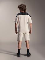 Alpinestars A-Aria Polartec Elite kortærmet jersey, MTB-cykeltrøje, Ecru med sorte skulderpaneler, set bagfra med matchende shorts og sorte strømper, ydeevnepasform med drop tail-design til terrænkørsel