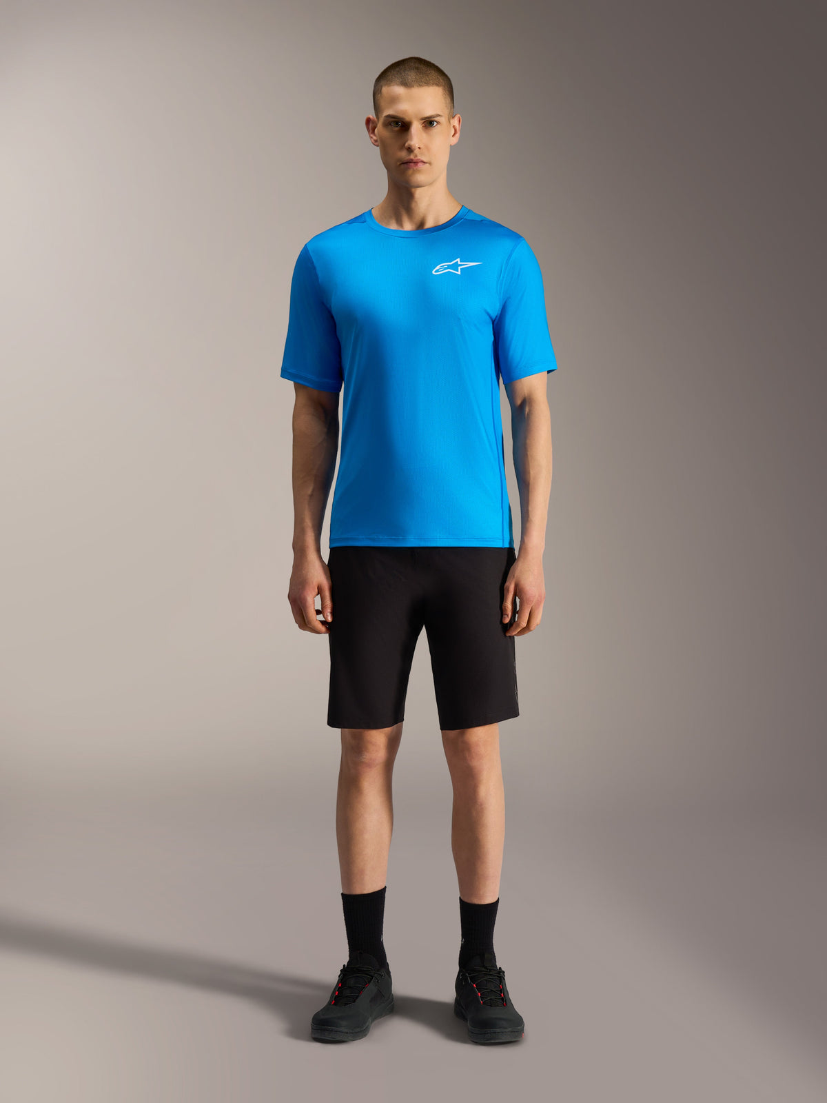 Alpinestars A-Dura Ride shorts i sort og klar blå jersey, performance mountainbike-tøj vist på en model.