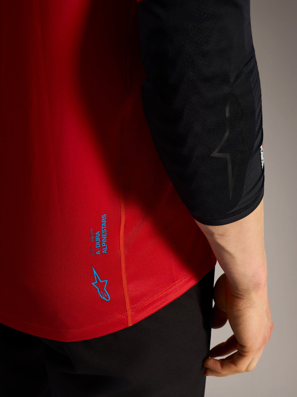 Rød A-Dura Ride jersey-detalje med blå Alpinestars-logoer og teknisk performance-stof til MTB.