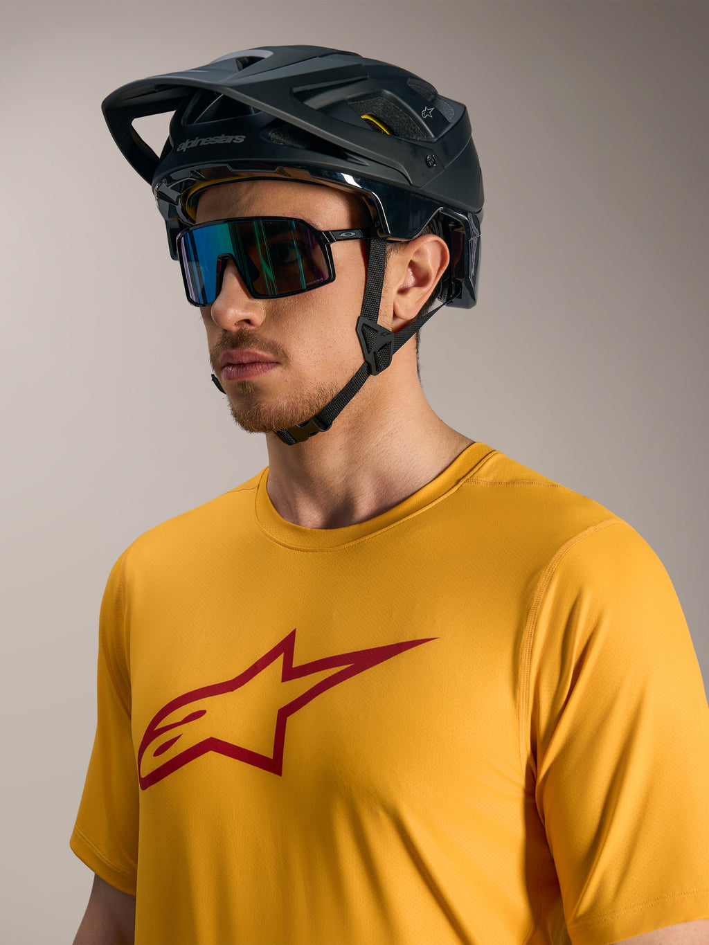 Orange A-Dura Ride trøje med rødt Astars-logo, sort MTB-hjelm og performance-solbriller til mountainbike.