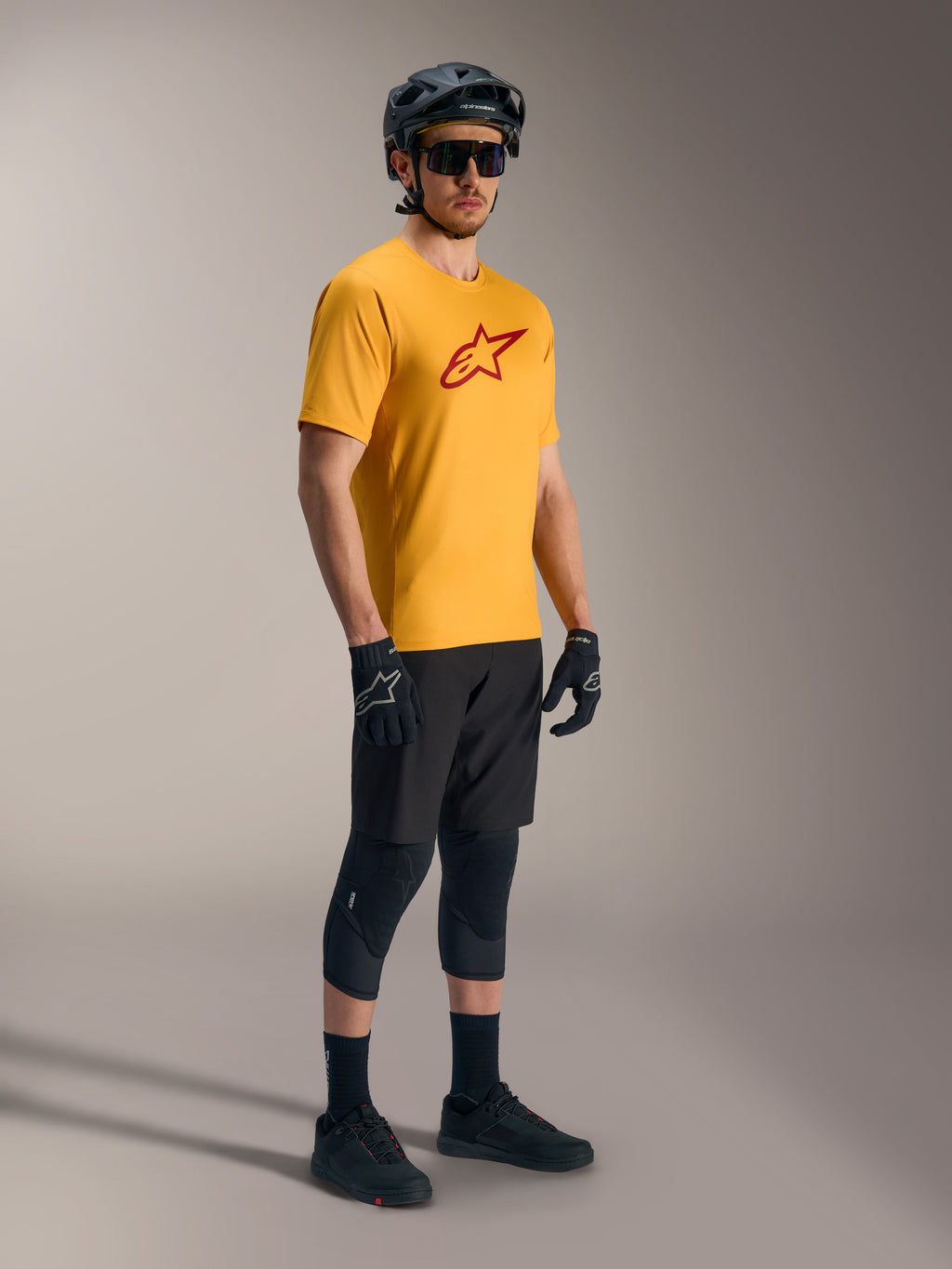 Alpinestars A-Dura Ride jersey i orange med rødt Astars-logo, sort mountainbike-udstyr og hjelm.