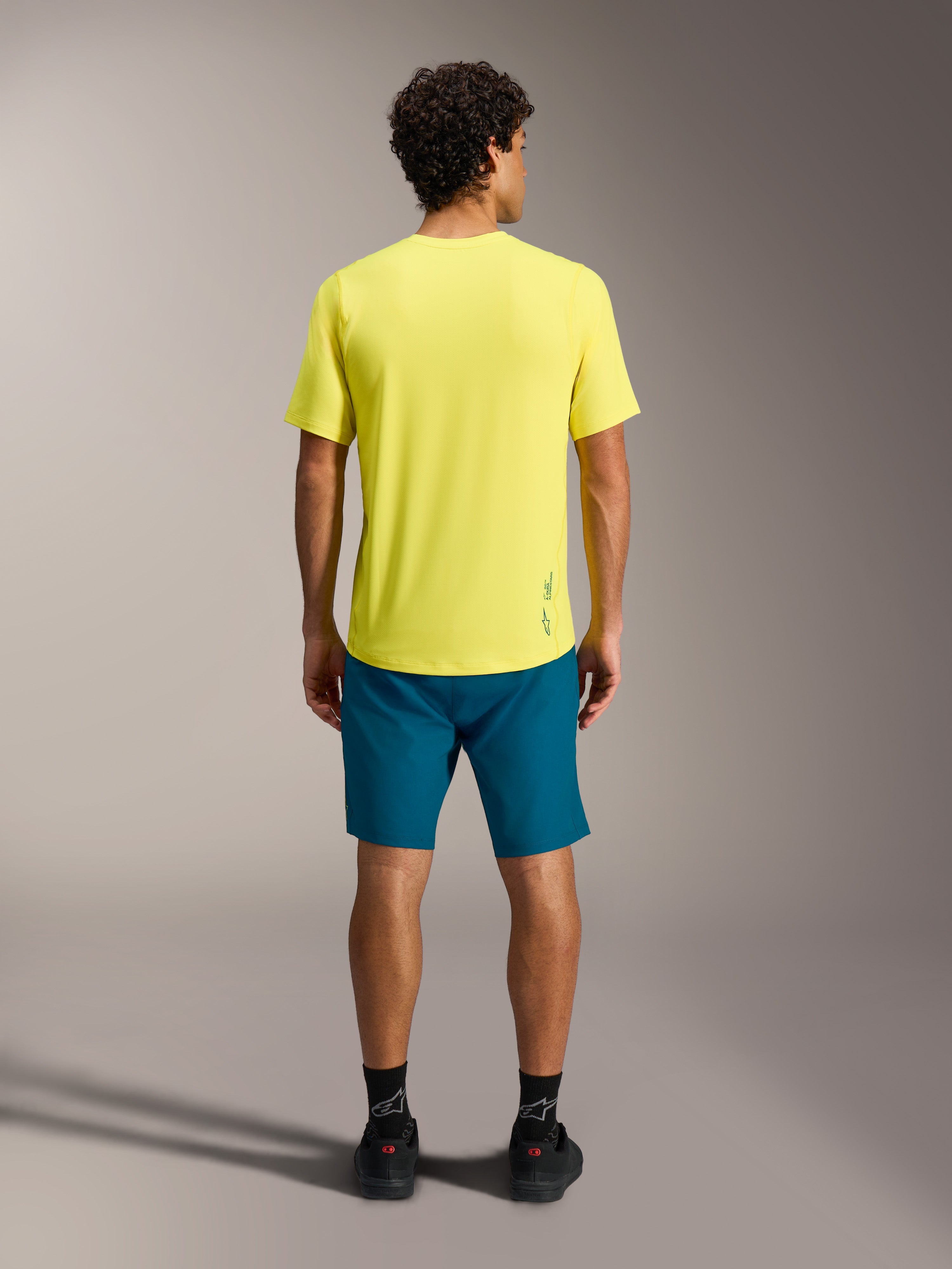 Gul A-Dura Ride SS trøje og blågrønne A-Dura Ride shorts set bagfra, funktionelt MTB-performanceudstyr.