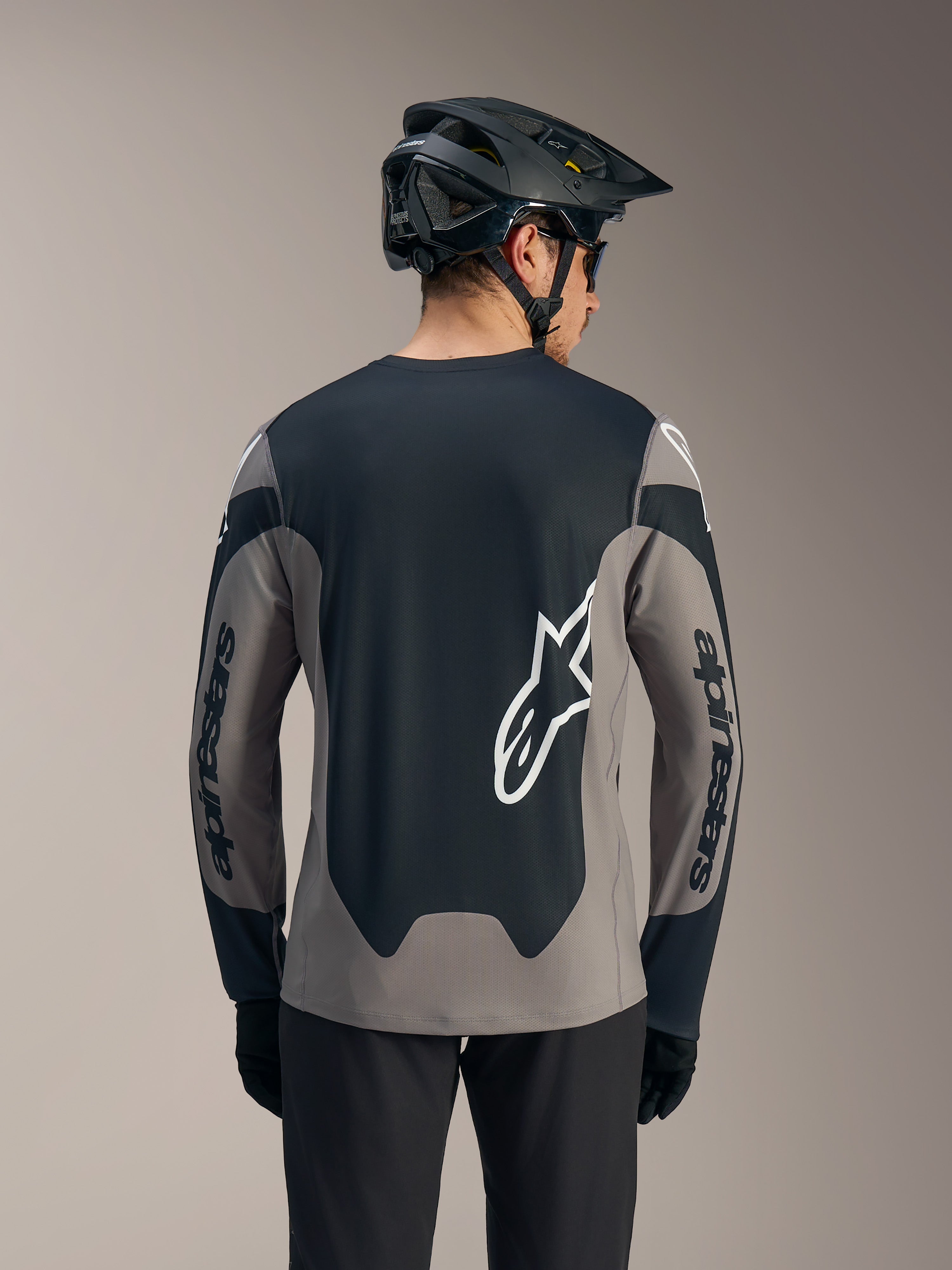 A-Dura Race langærmet trøje i grå og sort med markante hvide Alpinestars-logoer på ryggen og ærmerne.