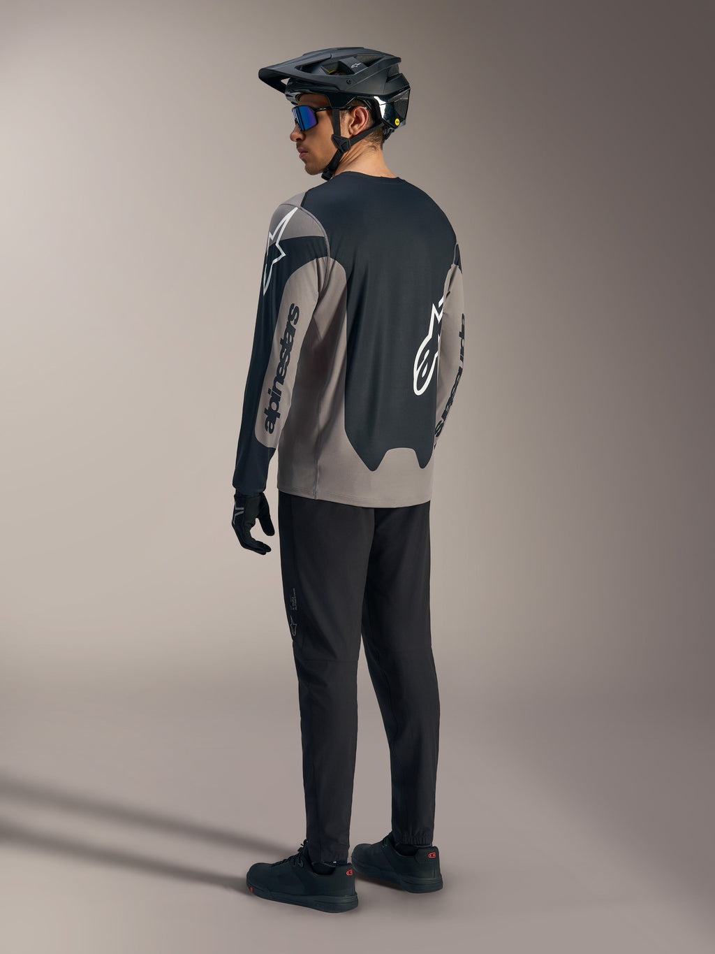 Grå og sort A-Dura Race langærmet trøje med Alpinestars-branding, vist bagfra i et komplet MTB-sæt.