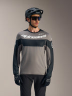 Alpinestars A-Dura Race langærmet trøje i grå og sort med hvidt logo, stylet med MTB-hjelm til kørsel på stier.
