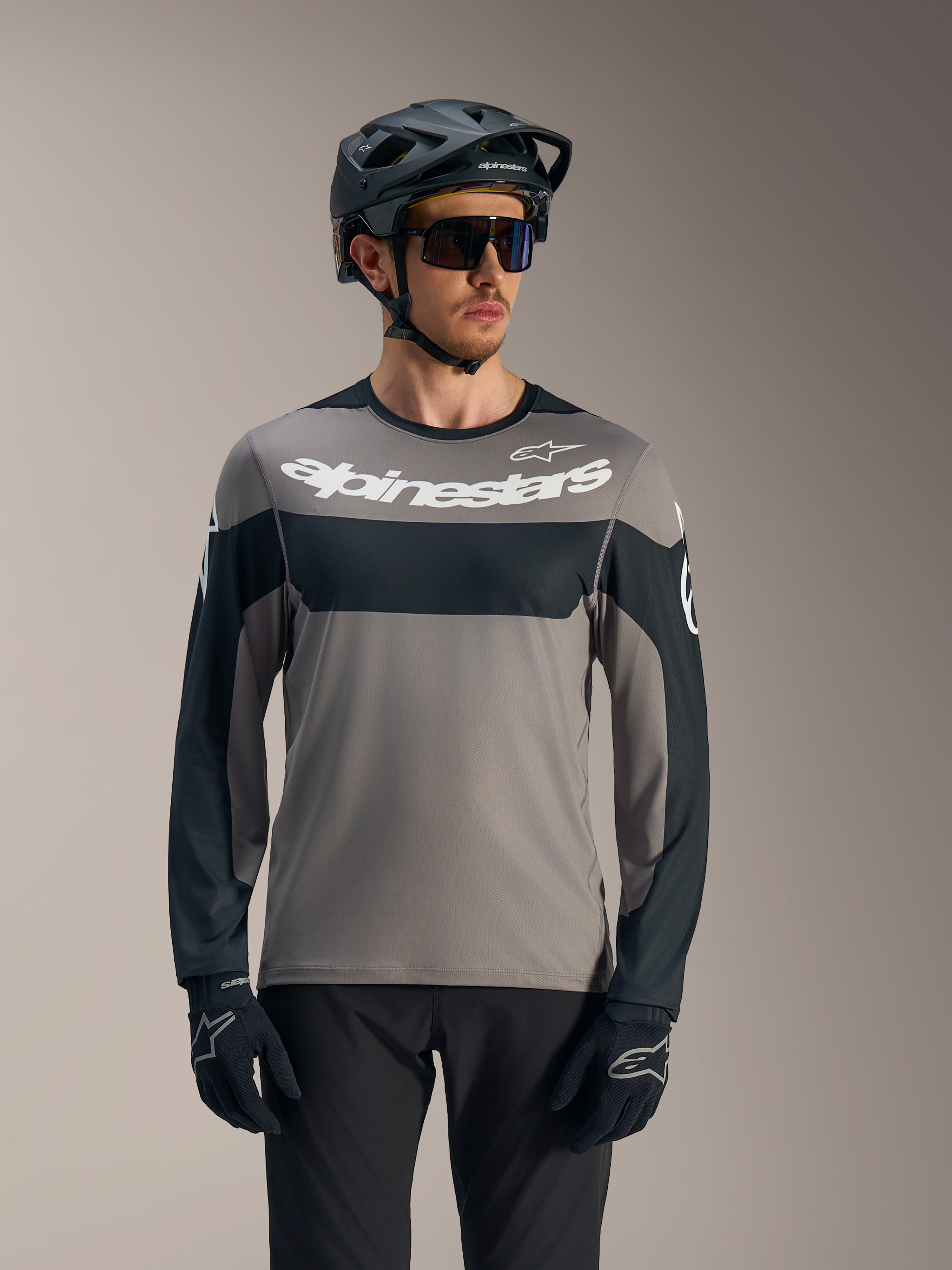 Alpinestars A-Dura Race langærmet trøje i grå og sort med hvidt logo, stylet med MTB-hjelm til kørsel på stier.