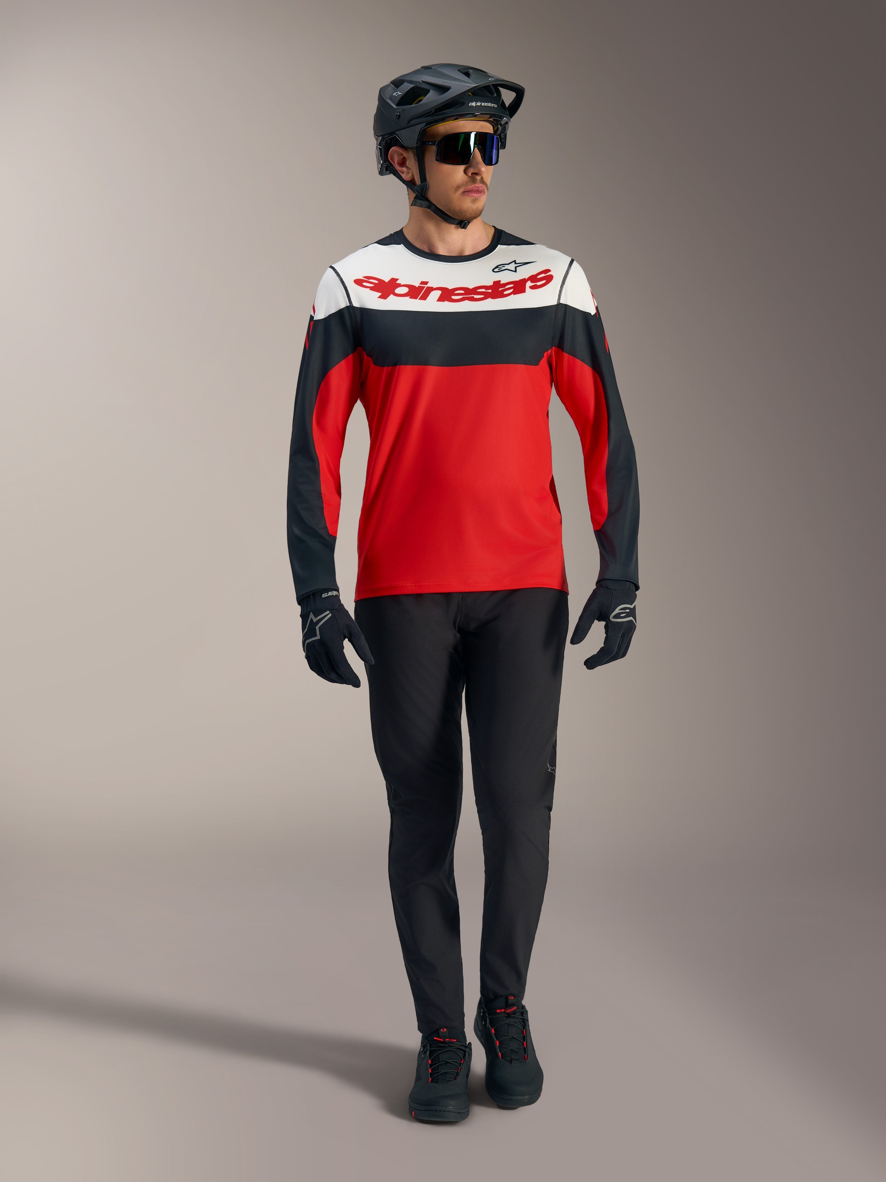 Alpinestars A-Dura Race langærmet trøje i rød med hvide og sorte paneler, parret med MTB-bukser og racingudstyr.