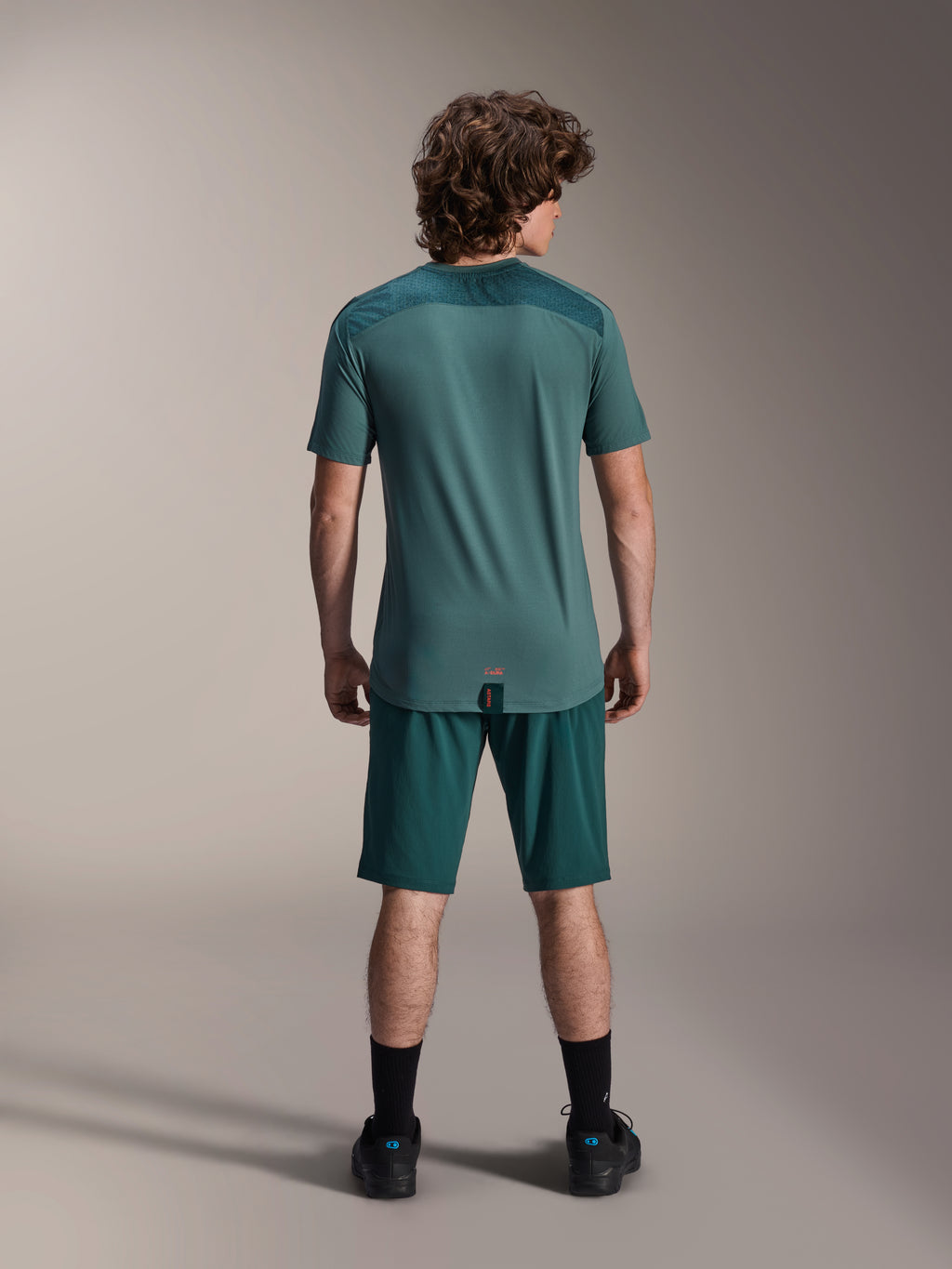 Alpinestars A-Dura shorts og A-Dura Lipan SS jersey, mørkegrøn (Dark Pine), set bagfra på en model, højtydende mountainbike-tøj med kortærmet jersey og matchende shorts, off-road cykeloutfit