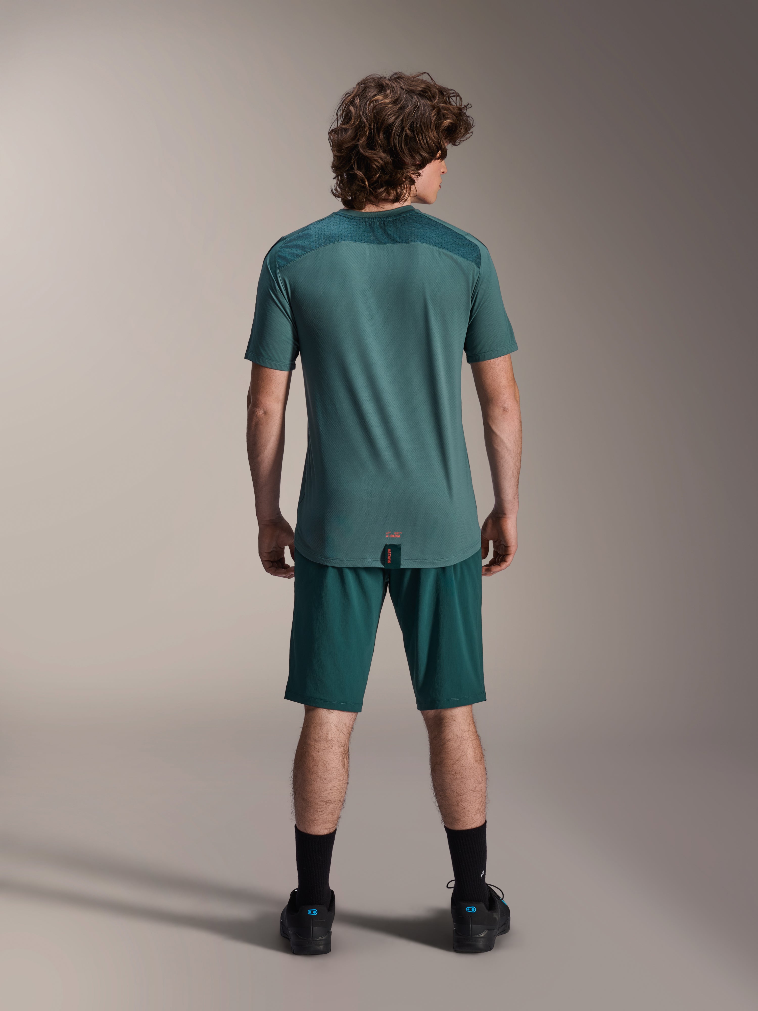Alpinestars A-Dura shorts og A-Dura Lipan SS jersey, mørkegrøn (Dark Pine), set bagfra på en model, højtydende mountainbike-tøj med kortærmet jersey og matchende shorts, off-road cykeloutfit