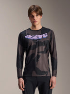 Alpinestars A-Dura Hollow Camo langærmet trøje, MTB mountainbike-trøje, sort og gråt camouflage-mønster, lilla 'astars'-grafik på brystet, båret af model med sorte bukser, afslappet performance-design