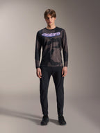 Alpinestars A-Dura Hollow Camo langærmet jersey i Black Camo, model iført mountainbike-udstyr med lilla 'astars' logo på brystet, sorte bukser og sorte cykelsko