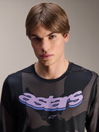 Alpinestars A-Dura Hollow Camo langærmet jersey, Black Camo med lilla 'astars' grafik på brystet, studiobillede af mandlig model i MTB-tøj, afslappet og teknisk mountainbike-stil