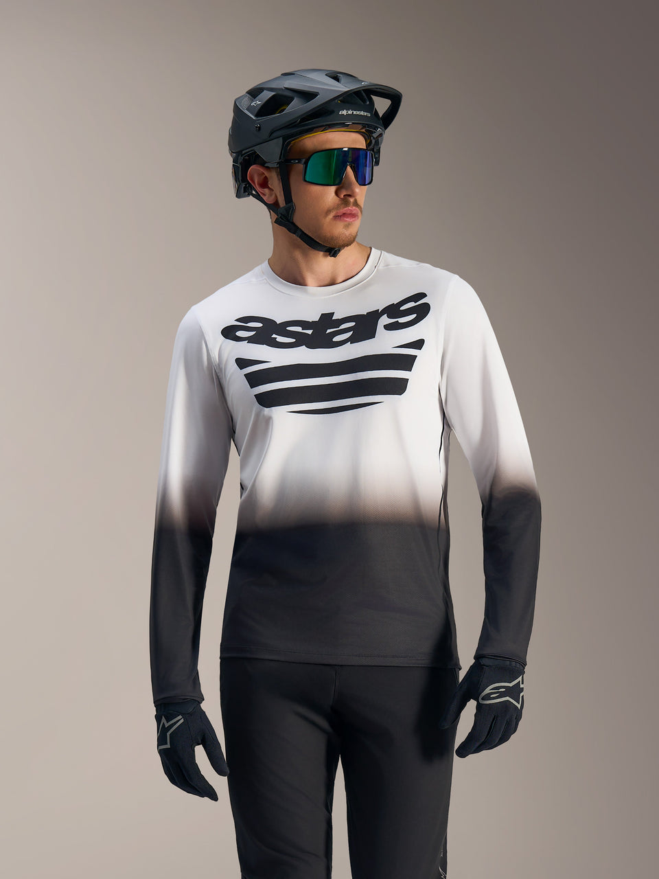 White and black gradient A-Dura ASTARS 2.0 Long Sleeve Jersey with bold chest logo, worn with mountain bike gear.