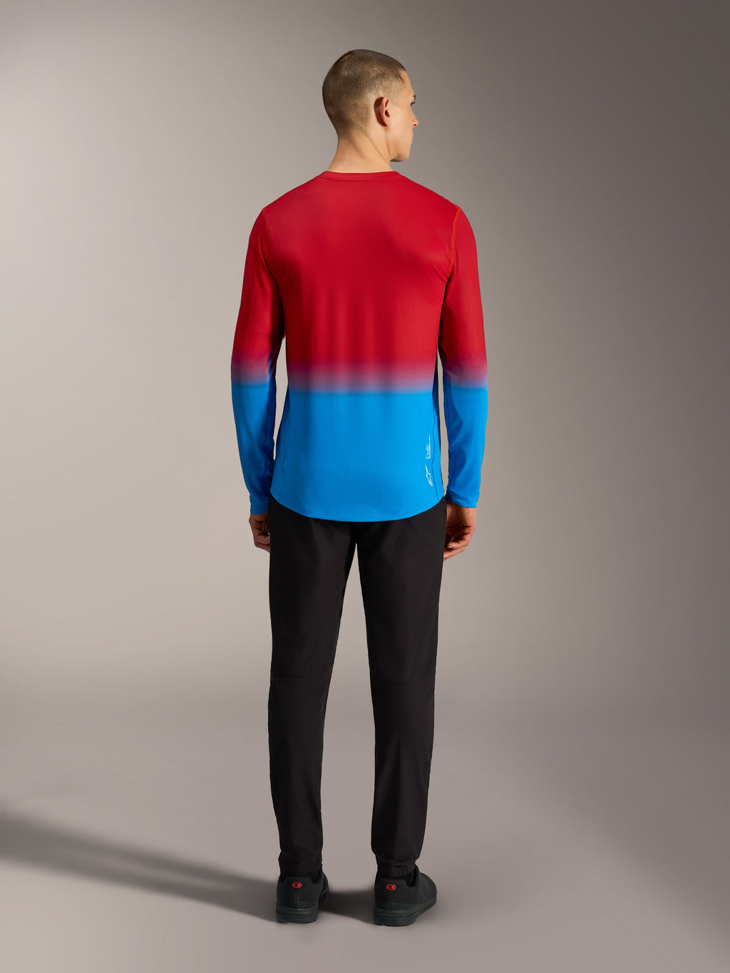 Alpinestars A-Dura ASTARS 2.0 langærmet MTB-jersey i rød og blå gradient, set bagfra på model.