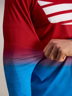 Fleksibelt rødt og blåt poly-spandex stof på Alpinestars A-Dura ASTARS 2.0 langærmet jersey, der viser stoffets stræk.
