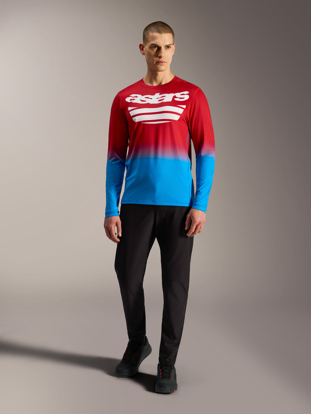 A-Dura ASTARS 2.0 langærmet MTB-trøje i rød og blå farveovergang med hvide logoer, vist med sorte bukser.