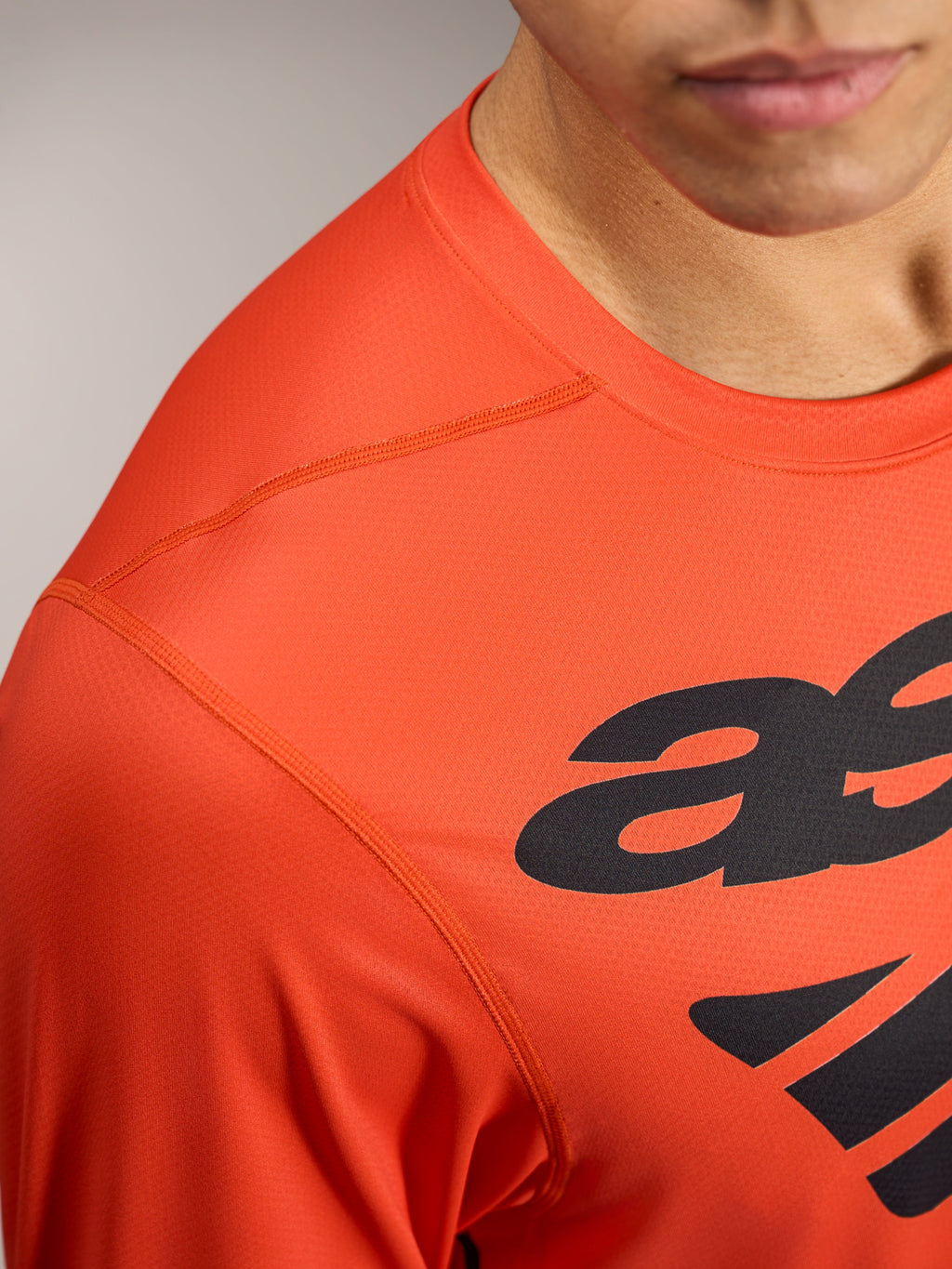Orange A-Dura ASTARS 2.0 langærmet jersey med sort logografik og åndbart, tekstureret performance-stof.