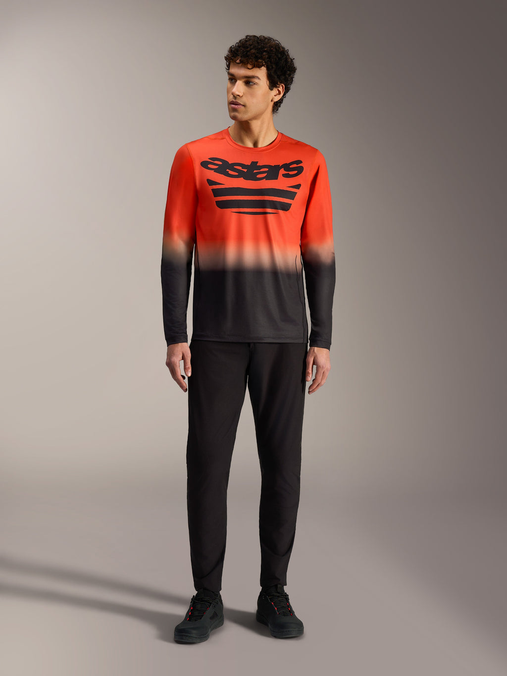 A-Dura ASTARS Langærmet Jersey 2.0 i orange og sort gradient med stort brystlogo og sorte MTB-bukser.