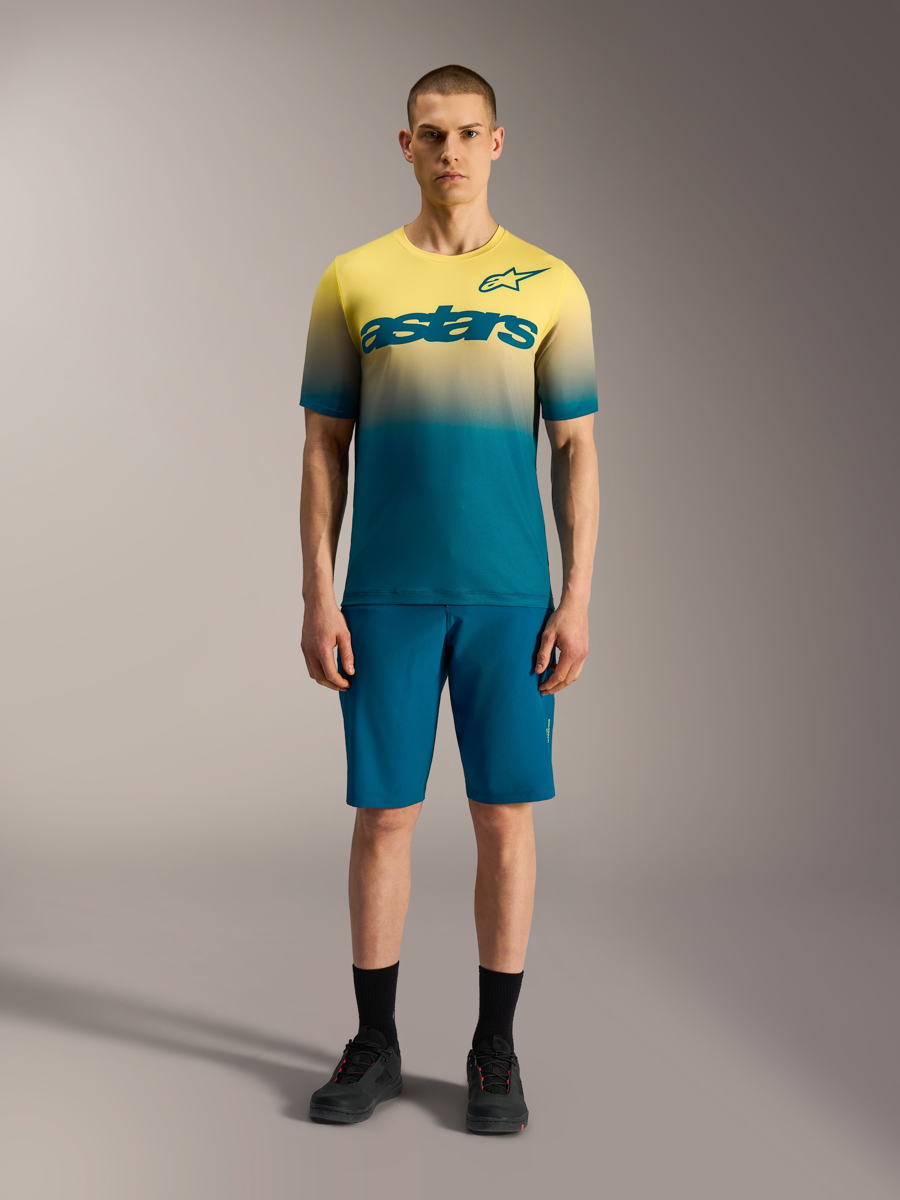 A-Dura ASTARS 2.0 Jersey, kortærmet MTB-trøje med gul og blå gradient og markant Alpinestars-logo på brystet.