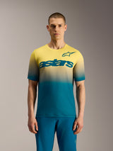 Alpinestars A-Dura ASTARS Jersey 2.0, kortærmet MTB-trøje med blågrøn til neongul gradient og stort brystlogo.