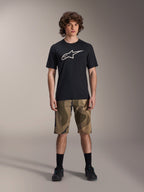 Alpinestars A-Dura Astar kortærmet jersey, sort med stort hvidt Astars-logo på brystet, båret af en model med camouflage MTB-shorts og sorte cykelsko, afslappet mountainbike-beklædning.