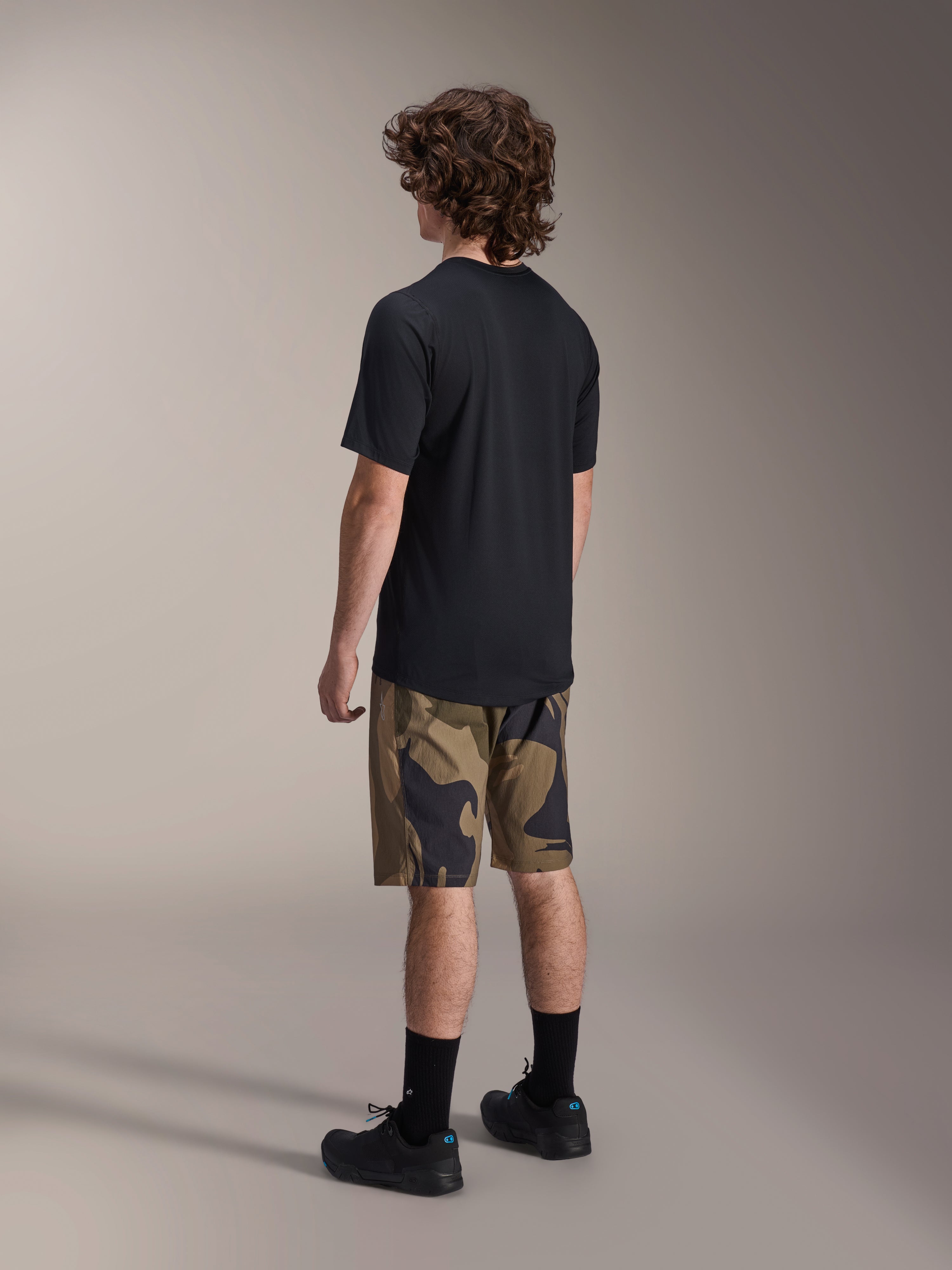 Alpinestars A-Dura Astar kortærmet trøje i sort, set bagfra, parret med shorts i camouflagemønster og sorte sportssokker og sko, afslappet MTB-udstyr