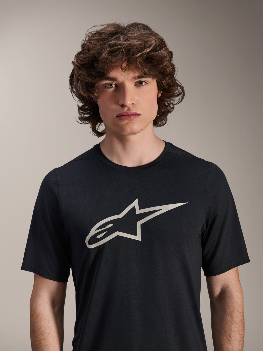 Alpinestars A-Dura Astar kortærmet trøje, sort, med et stort hvidt Astar-logo på brystet, båret af en mandlig model, afslappet mountainbike-performance-beklædning