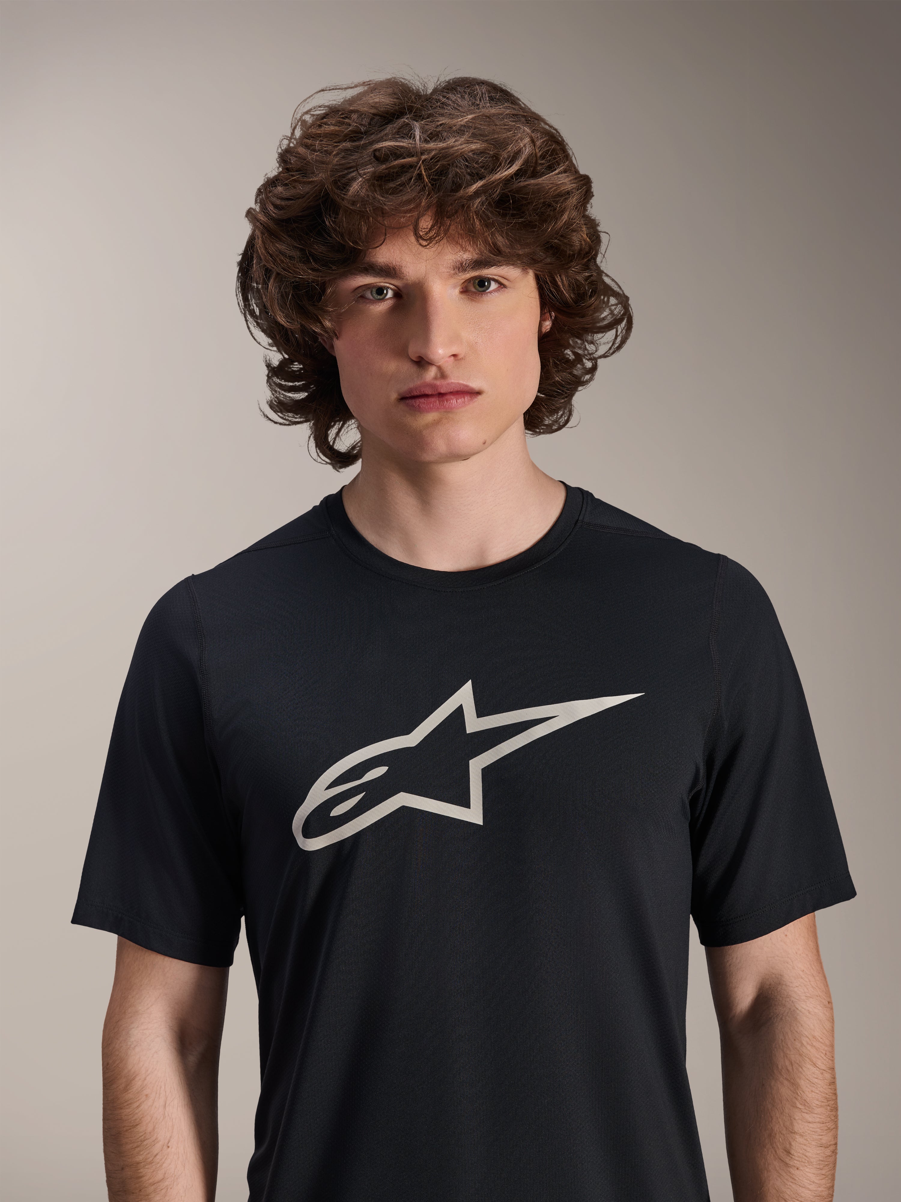 Alpinestars A-Dura Astar kortærmet trøje, sort, med et stort hvidt Astar-logo på brystet, båret af en mandlig model, afslappet mountainbike-performance-beklædning