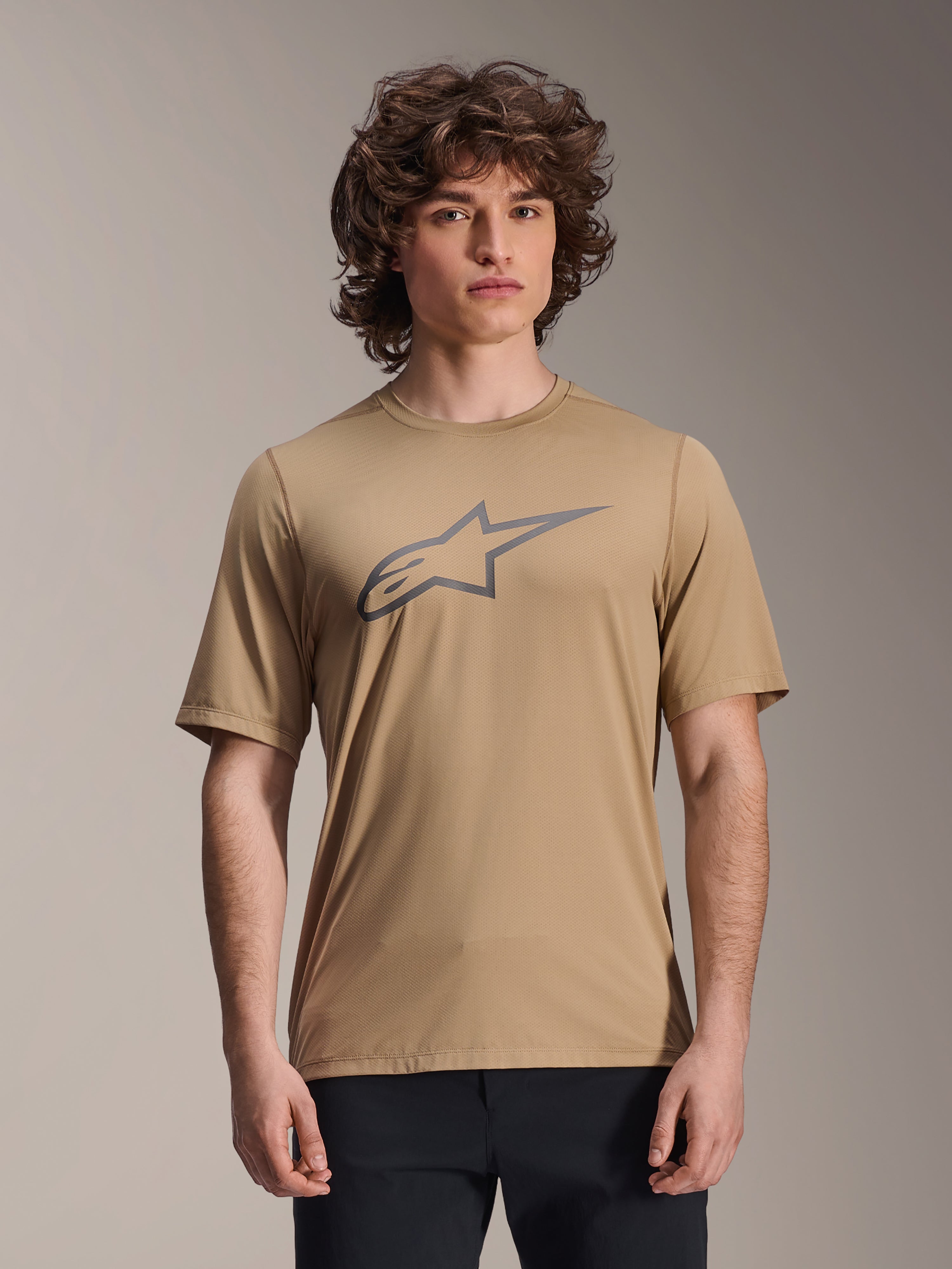 Alpinestars A-Dura Astar Short Sleeve Jersey, Light Brown, worn by male model with black pants, grey Alpinestars star logo on the chest, casual mountain bike jersey for trail riding
