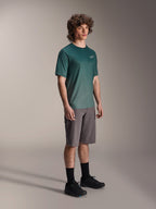 Alpinestars A-Dura Rise Jersey - kortærmet i Silver Pine, grøn mountainbike-jersey båret af en model med grå shorts og sorte sneakers, afslappet MTB-udstyr til trailkørsel, lille hvidt logo på brystet