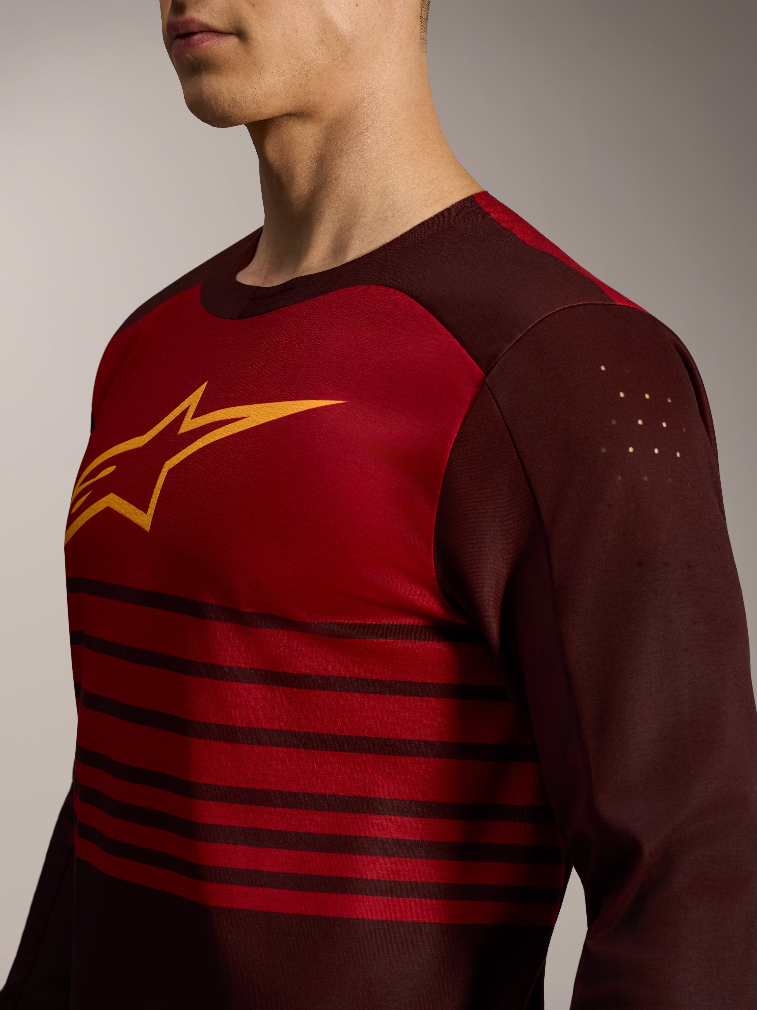 A-Dura Elite Jersey 2.0 i bordeaux med lange ærmer, gult logo og laserudskårne perforeringer på overarmen.