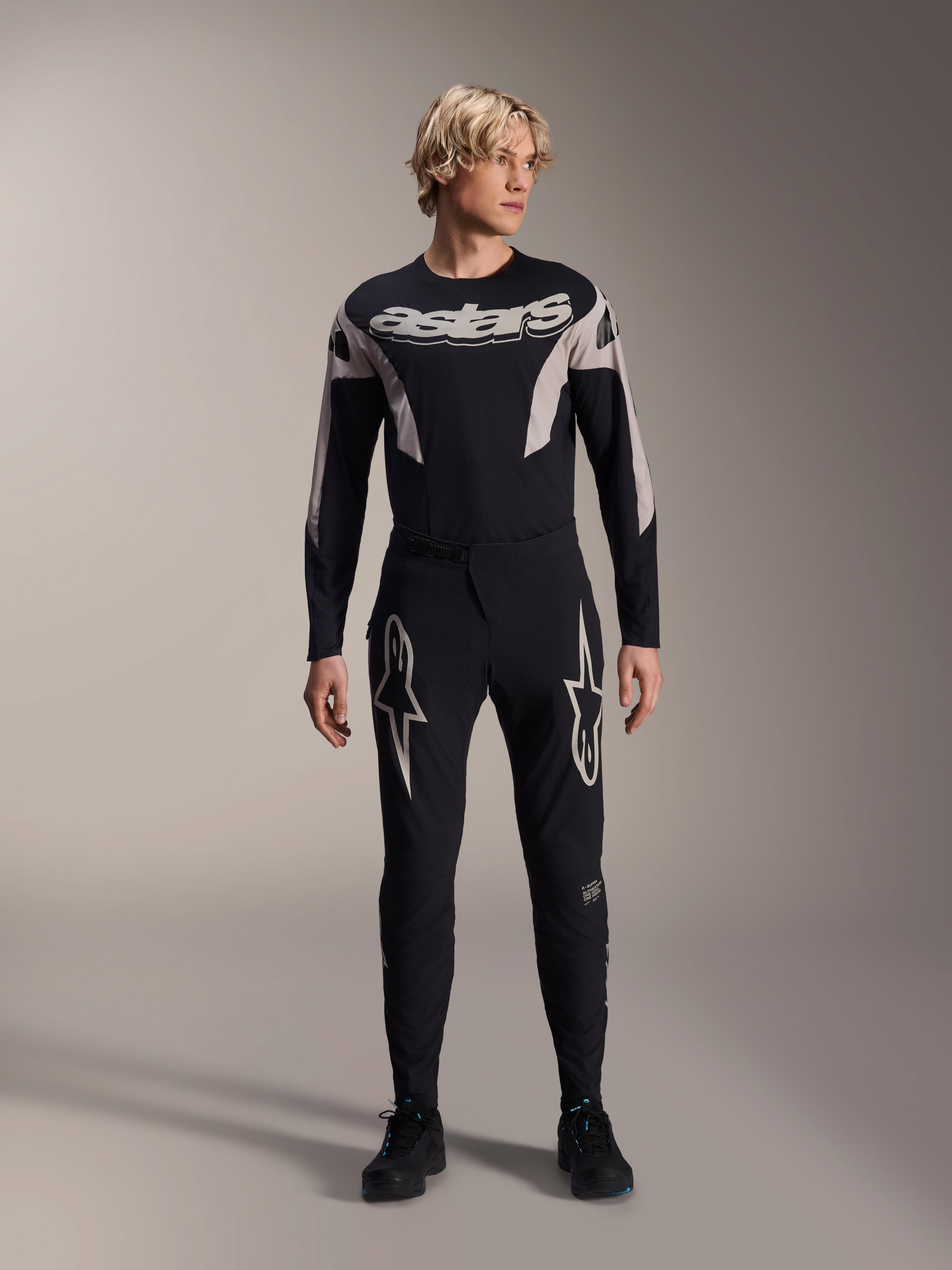 Alpinestars A-Supra Melt bukser og matchende langærmet jersey, model iført sort MTB-sæt med store hvide stjernegrafikker på lårene og 'astars' branding på brystet, professionelt mountainbike-racerudstyr
