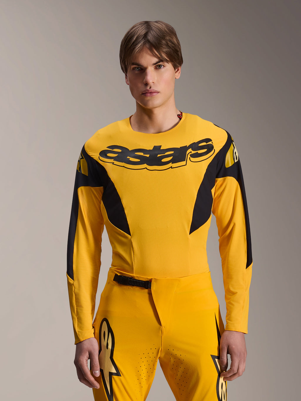 Alpinestars Limited Edition A-Supra Melt Gold Jersey, langærmet MTB-trøje, mørkegul med sorte detaljer, båret af en model med matchende bukser, med stort sort 'astars'-logo på brystet og atletisk performance-design