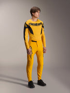 Model iført Alpinestars Limited Edition A-Supra Melt Gold trøje, langærmet MTB-trøje i mørkegul og sort, matchende gule bukser og sorte sko, teknisk off-road cykeludstyr med racing-inspireret grafik