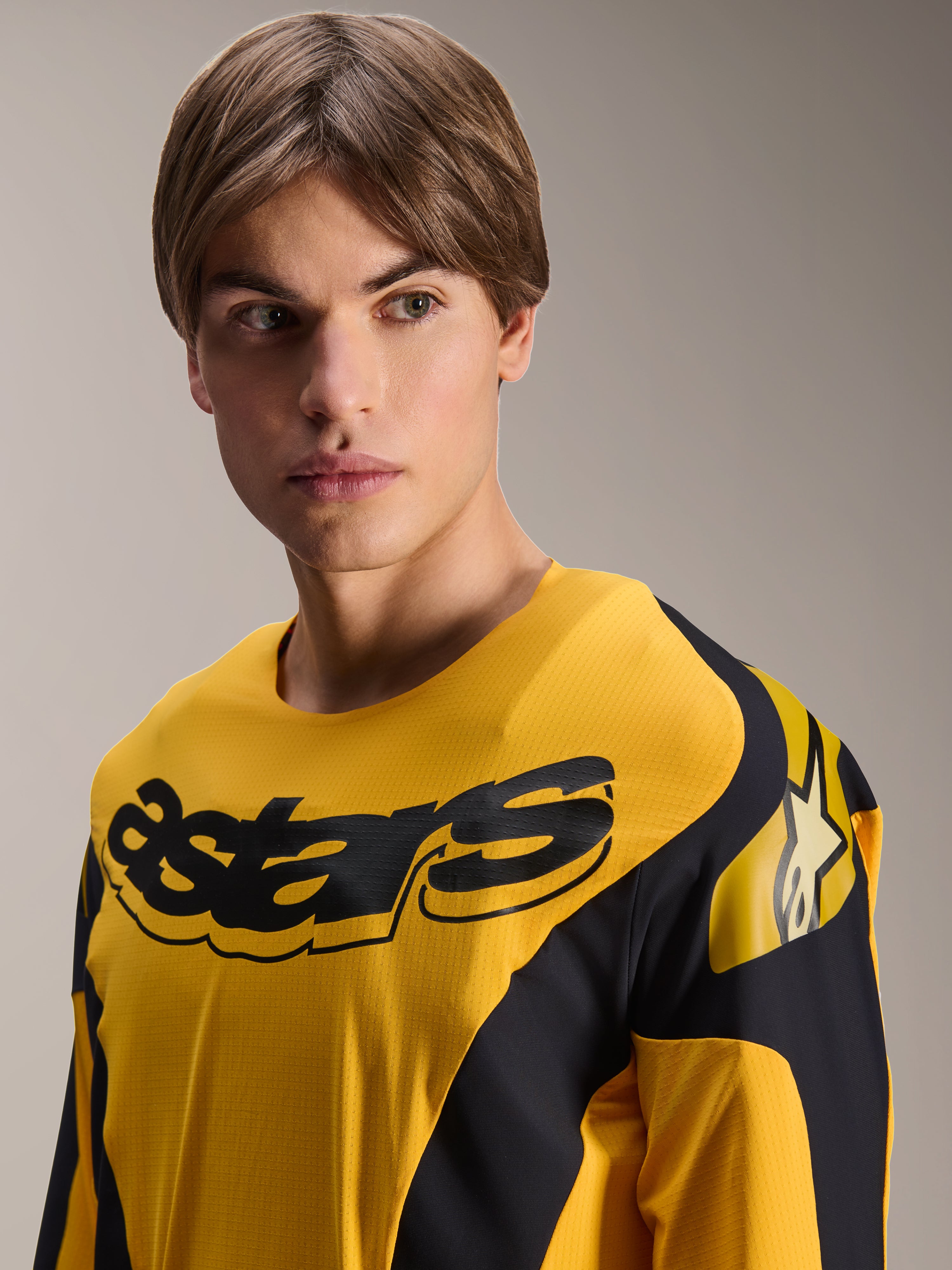Alpinestars Limited Edition A-Supra Melt Gold Jersey, langærmet MTB-trøje, mørkegul med sort racing-inspireret grafik, med sort 'astars'-ordmærke på brystet og stjernelogo på skulderen, båret af en mandlig model