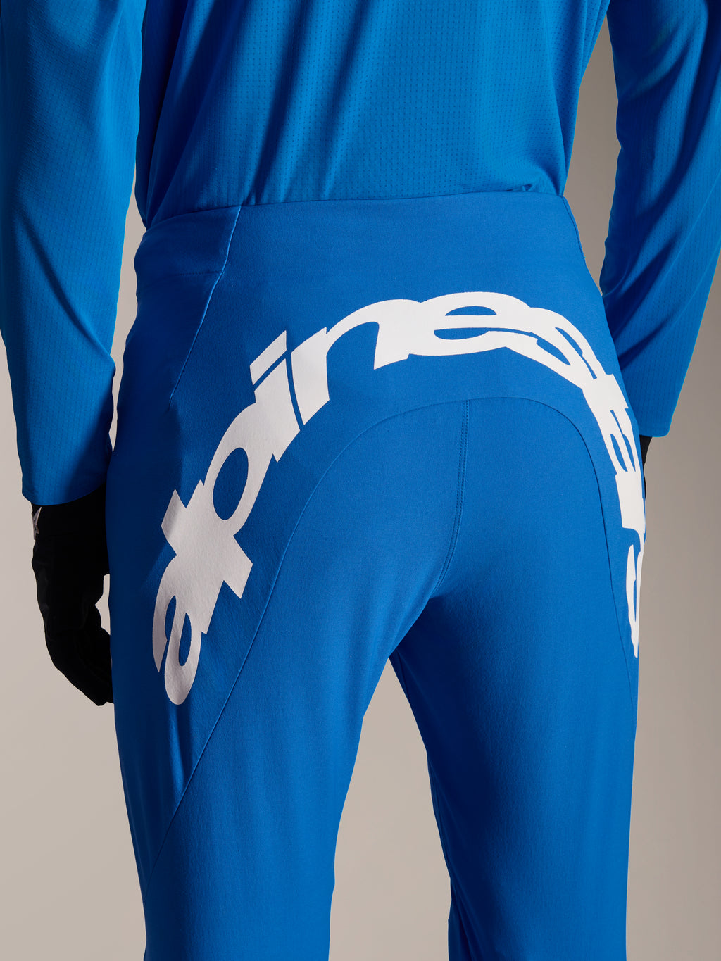 Alpinestars A-Supra Melt bukser og trøje, blåt MTB-udstyr, set bagfra med stort hvidt Alpinestars-ordmærke på buksernes bagstykke, matchende langærmet trøje og sorte handsker