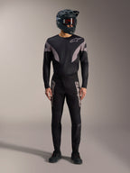 Sort Alpinestars A-Supra Elite MTB-sæt med langærmet trøje, racerbukser med grå logoer og full-face hjelm.